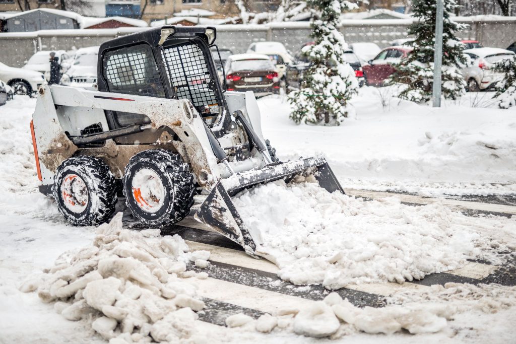 Skid loader moving snow with bucket