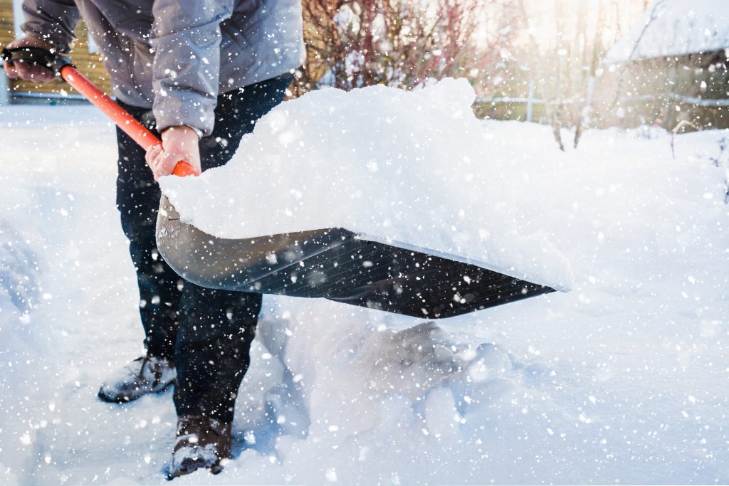 Snow removal. Man clearing snow by shovel after snowfall. Outdoors.